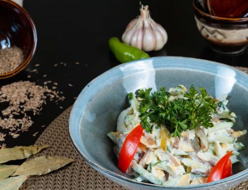 A vibrant salad with fresh vegetables, herbs, and spices, beautifully plated.